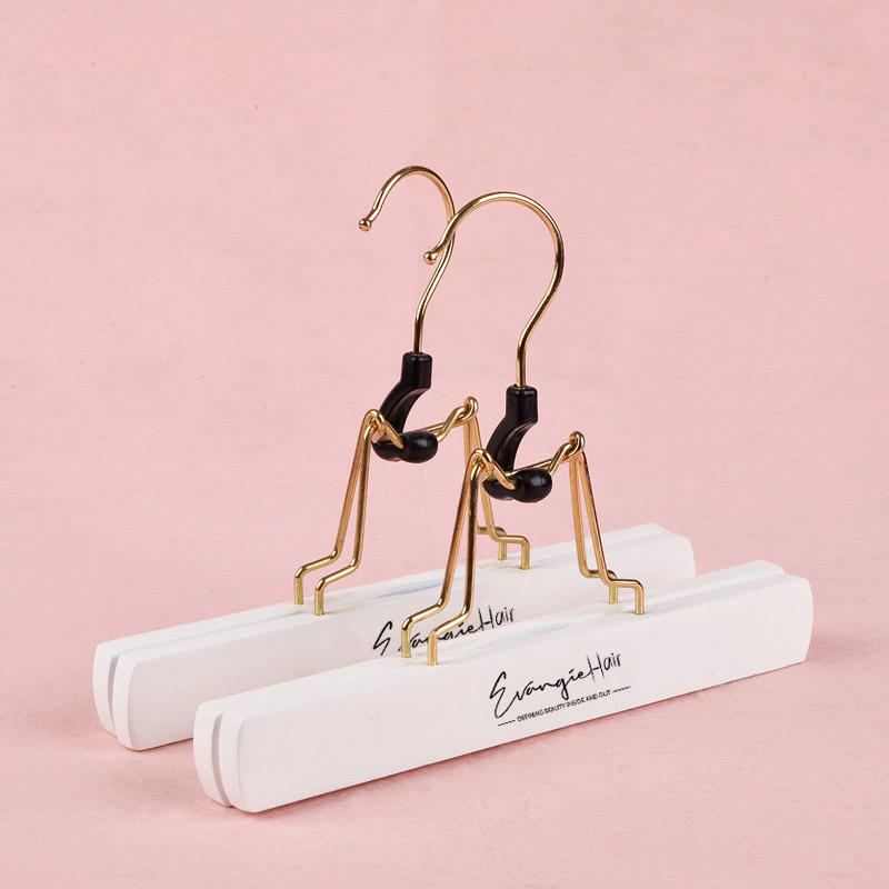 Two wig hangers in gold, black and white